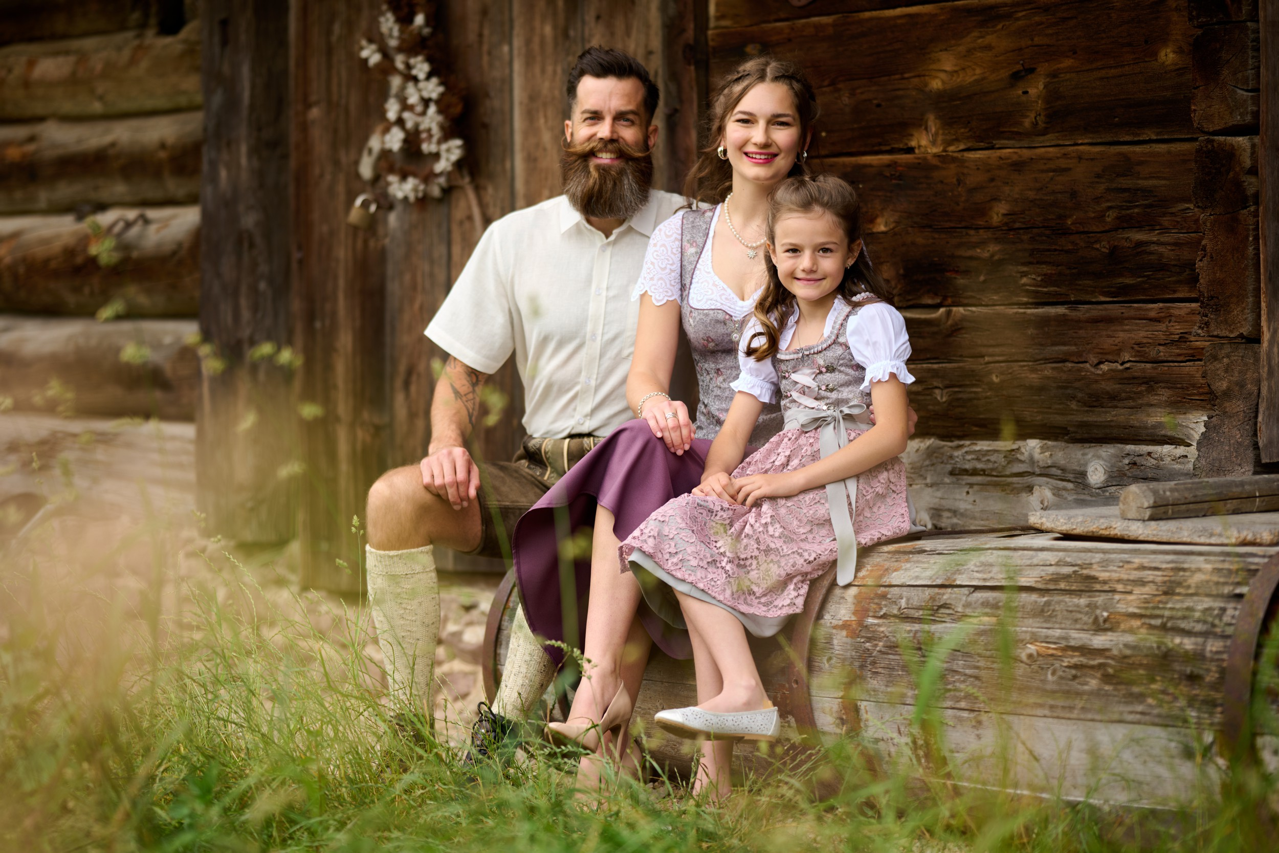 Eine Familie mit Kind vor einem Bauernhof sitzend
